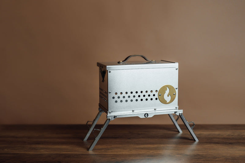 The Hekla: 304 Stainless Steel LavaBox with Dual-Burner on display with a leather handle and brass finishes.