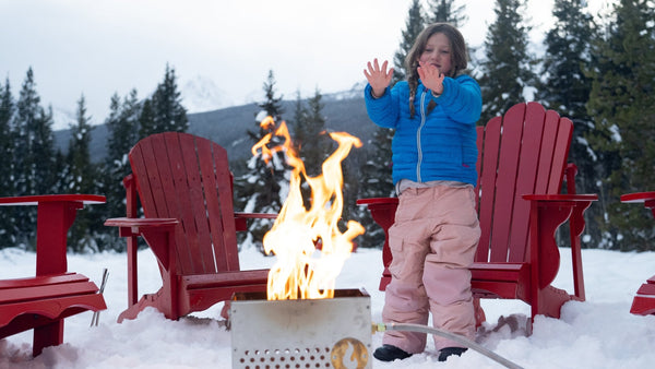 The Hekla: 304 Stainless Steel LavaBox with Dual-Burner in use with a child warming hands by the fire.