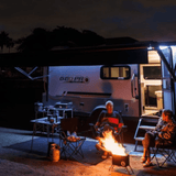 Camping at night with a GEO PRO trailer, a campfire, and two friends enjoying the outdoors.